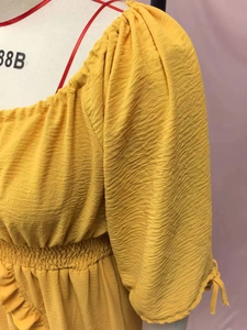 Macro shot of ginger yellow textured fabric with elastic pleated waist and tie-up cuffs