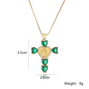 Close-up of 18K gold plated cross pendant with heart center and green cubic zirconia