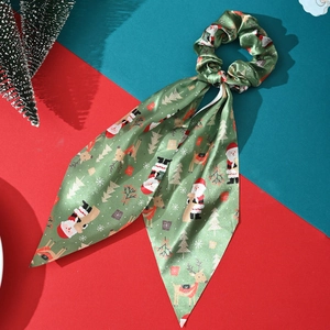Detail view of green Christmas silk scrunchie with ribbons and festive holiday pattern