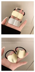 Close-up of brushed metal hair ties in gold and silver showing rectangle and heart shapes