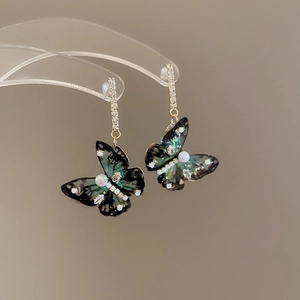 Detail of green iridescent butterfly earrings with small pearls and crystals on gold posts