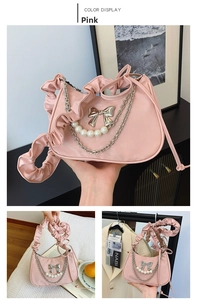Detailed view of pink crescent bag featuring silver bow, pearls, and ruffled shoulder strap