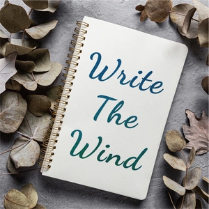 Detailed top view of a gold spiral notebook with Write The Wind cover and dried leaves