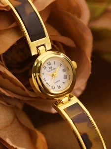 Macro shot of gold quartz watch with tortoise shell strap and roman numeral dial