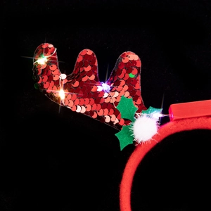 Close-up of LED Christmas headband with red sequin reindeer antlers and holly leaves