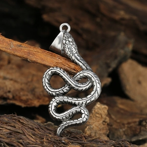 Silver cobra pendant necklace with detailed scales on a natural wood surface