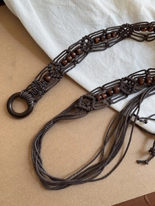 Detail of bohemian handmade woven waist chain with dark wood beads and circular wood buckle