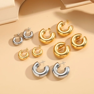Polished gold and silver C-shaped tube earrings in four graduated sizes on display