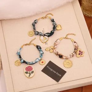 Detailed view of silk wrap bracelets with rose, heart, and daisy enamel pendants