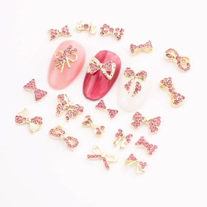 Macro detail of pink rhinestone bow nail charms with gold alloy bases for DIY manicures
