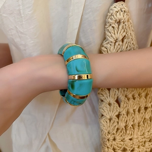 Close-up of vintage acrylic bangle with blue-green resin and gold metal accents