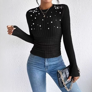 Detail of elegant white pearls scattered on a black ribbed long sleeve knit top