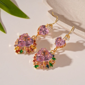 Macro detail of heart-shaped pink zircon earrings with colorful gems on stone background