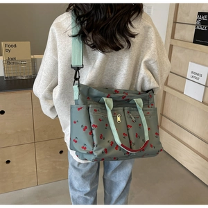 Detail of green nylon tote bag with cherry print and adjustable wide strap