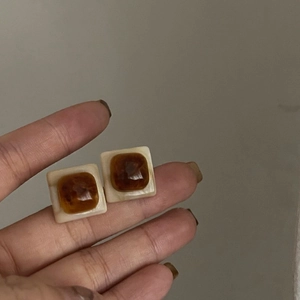 Détail de boucles d'oreilles carrées blanc crème avec pierres en résine ambrée rétro