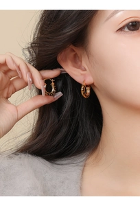 Close-up of 14k gold plated round hoop earrings with leopard print texture on a model