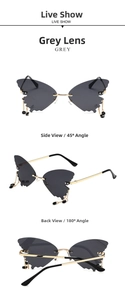Detail of butterfly-shaped sunglasses with grey lenses, gold frame and bead tassels