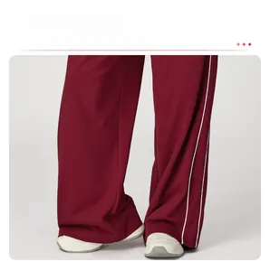 Détail du jogging bordeaux à jambes larges avec bandes latérales et tissu fluide