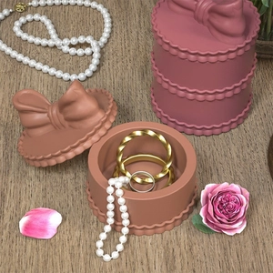 Detail of stacked bow resin jewelry organizers and pink storage containers on wooden table