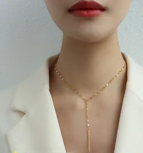 Détail du collier en Y doré élégant porté par un mannequin en blazer blanc chic