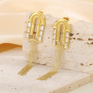 Détail de boucles d'oreilles dorées à pompons avec zircon carré sur une pierre