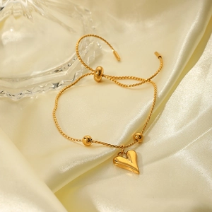 Elegant gold heart pendant bracelet with adjustable bead chain on silk background
