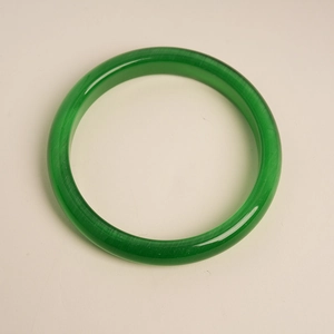 Detailed view of emerald green cat-eye stone bangle with glossy finish and fiber texture