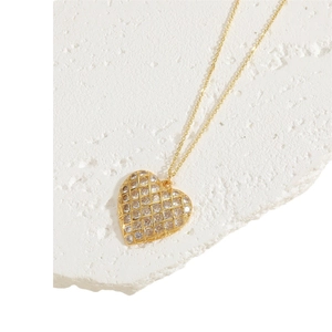 Exquisite gold heart necklace with zircon inlay on a white textured stone background