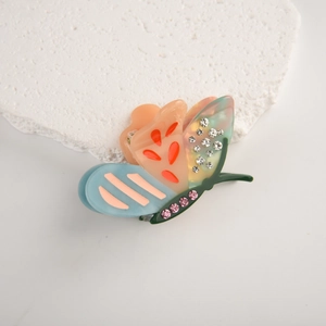 Detailed view of rhinestone-studded butterfly hair claw clip on marble background