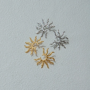 Detailed flat lay of sun-shaped hollow earrings in gold and silver stainless steel