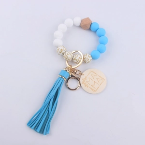 Close-up of silicone beaded keychain bracelet with MAMA wooden tag and blue tassel detail