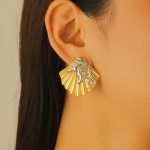 Detail of a golden scallop earring with silver coral accents and pearls on a model