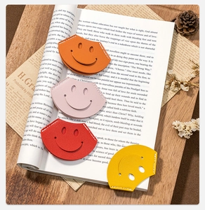 Close-up of four colorful PU leather corner bookmarks with smiley faces on a magazine
