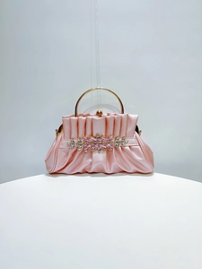 Detail of pink satin evening clutch with rhinestones and golden round handle