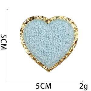 Gedetailleerde weergave van 5cm blauwe chenille hartpatch met gouden glitterrand, 2g