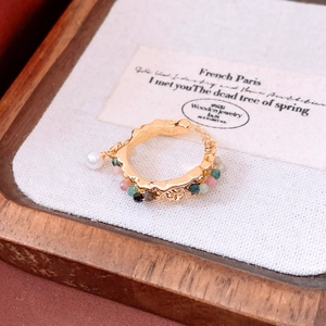 Detail of 18k gold plated open ring with colorful beads and a small hanging pearl charm