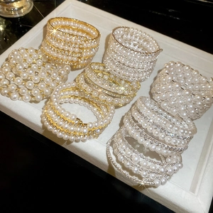 Detailed close-up of multilayered pearl and rhinestone wrap bracelets in gold and silver