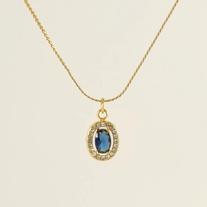 Macro detail of 18K gold double-layer chain necklace with blue oval zircon pendant