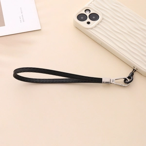 Detail of black leather phone wrist strap with silver metal clasp on wavy phone case