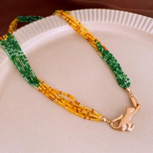Detail of multi-layer beaded necklace with green crystal beads and cat-shaped gold clasp