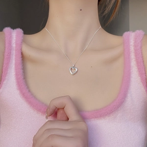 Collier avec pendentif coeur creux en argent 925 et gravure florale porté par un modèle