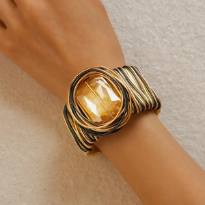 Macro shot of wide braided gold and black wire cuff bracelet with square amber gemstone