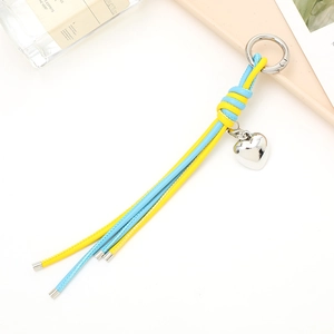 Detail showing blue and yellow braided leather keychain with silver heart pendant