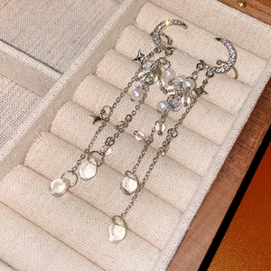 Detailed view of silver moon star tassel earrings with pearls and crystals in a box