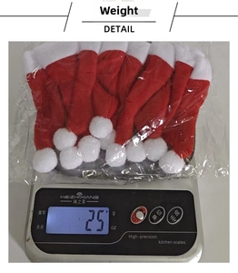 Detailed view of mini Christmas hats in plastic packaging being weighed at 25g on a scale