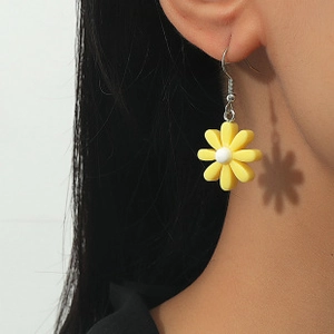 Detail view of yellow daisy resin earrings on model with artistic shadow projection