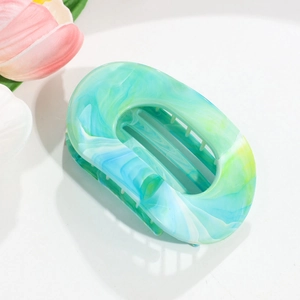 Detail view of oval flat hair claw clip with green and blue marble resin texture