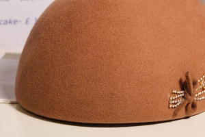 Detailed macro view of the rhinestone-studded bow on a premium wool beret hat