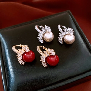 Macro shot of gold and silver earrings with marquise zircons and round pearls on leather