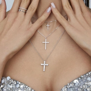 Macro detail of layered silver cross necklaces with micro-pave zircon on female neck